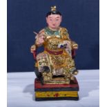 A carved Chinese wood figure of a scholar sitting in a Ming chair, highlighted in gilt, 8 inches