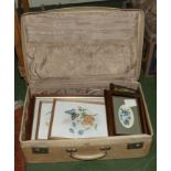 A suitcase with framed embroideries and other prints