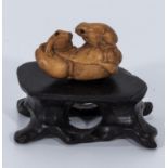 A small intricate hardwood netsuke of two frogs on stand