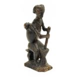 An antique carved figure of a mother and child crushing grain.