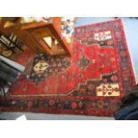 A Persian rug with a central medallion on a red ground, 112 x 62