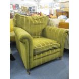 An early 20th century armchair upholstered in a brown and green fabric, raised on square tapered