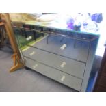 A modern mirrored chest of three long drawers and two matching side tables