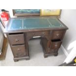 A mid 20th century oak kneehole desk with a green scriber over seven drawers, raised on bracket