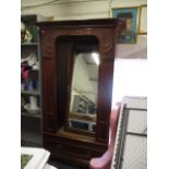 An Art Nouveau walnut wardrobe with a mirrored door and carved ornament, above a drawer, raised on