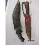 A Gurkha Kukri knife with two small knives in a leather sheath and another knife in a carved