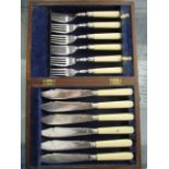 An oak cased set of six fish knives and forks with simulated ivory handles and silver bands,