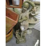 A concrete garden statue of a nude figurine in a classical pose, possibly Venus, with shell brocade,