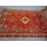 A red ground rug with geometric design, 92" x 60"