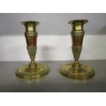 A pair of early 19th century French brass and copper candlesticks, decorated with banks of stiff