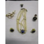 A simulated pearl three string chocker necklace with a blue past stone surrounded by faux pearls