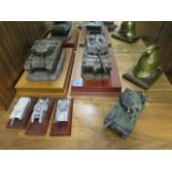 A small group of tank models, some pewter with a brass model of a helmet