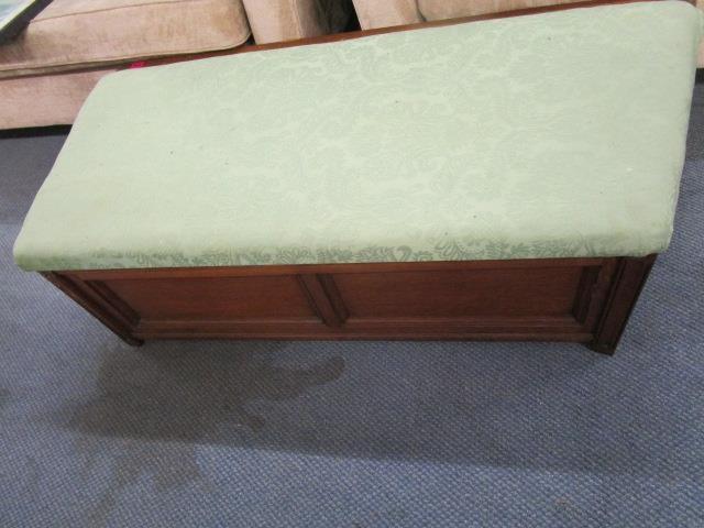 An early 20th century oak ottoman with an upholstered, hinged top and angled sides