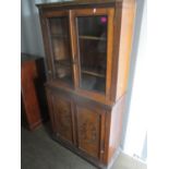 A Victorian oak bookcase having two glazed doors and two carved cupboard doors below on a plinth