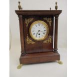 A mahogany cased mantle clock with turned finials, circular dial flanked by oak leaves and four