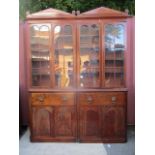 A Victorian mahogany reduced bookcase cabinet having a double arched cornice, over four glazed,