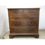 A George III mahogany chest of two short and three graduated long drawers with feather crossbanding,