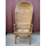 An early 20th century, light oak framed Orkney chair having a rush canopy back, scrolled arms and