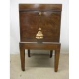 A George III boxwood, string inlaid mahogany cellerette having a hinged, arched top over straight