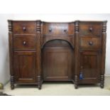 An early 19th century mahogany sideboard having an in-curved front with a drawer and a panelled