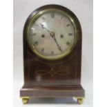 An Edwardian mahogany, string inlaid, arched topped mantle clock having a silvered dial with Roman