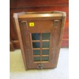 An oak Arts & Crafts cabinet with a green glass door and metal hinges