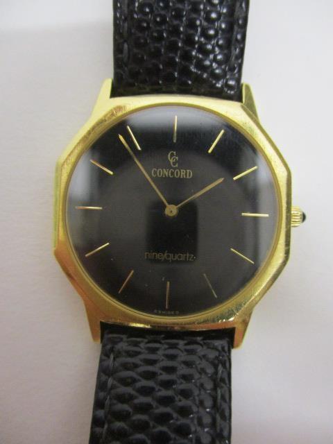 A Concorde gents quartz 18ct gold wristwatch having a black dial, gilt baton markers in an