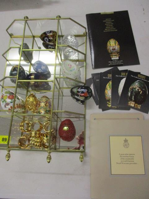 A collection of reproduction ornamental eggs with glass display stand and 'Collectors Treasury of