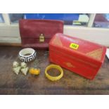 A gold tooled, red leatherette box containing a selection of costume jewellery to include an amber