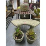 A stoneware garden bench, a pair of garden planters with plants, and a single stoneware planter of