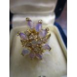 A yellow metal ring set with purple tinged coloured cabochons, boxed