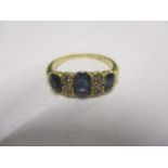 A diamond and sapphire yellow metal ring