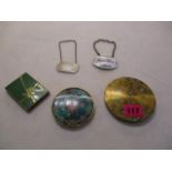 A small group of compacts together with two wine labels, one being silver