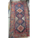 A Caucasian rug with five hooked diamond medallions on a blue ground, 88" x 45"