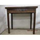 A George III mahogany tea table having a foldover top, over a frieze drawer, raised on square,