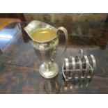 A silver cream jug of faceted form and a toast rack