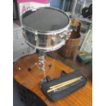 A snare drum and stand with two pairs of sticks and a bag