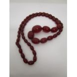 A cherry red phenolic Bakelite graduated beaded necklace, 57 beads, total weight 62.3g