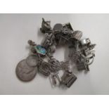 A silver fancy gate link charm bracelet with various charms and an Edward VII commemorative coin,