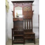 A Liberty's style Arts & Crafts walnut hall stand having a moulded cornice over a mirror, an