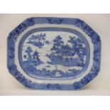 A late 18th century Chinese blue and white meat plate decorated with a lake, buildings, a bridge,