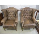 A pair of modern brown leather, wing back armchairs, raised on cabriole legs