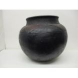 A 19th century South African black, brown/red glazed clay pot with incised decoration, 14" h, on a