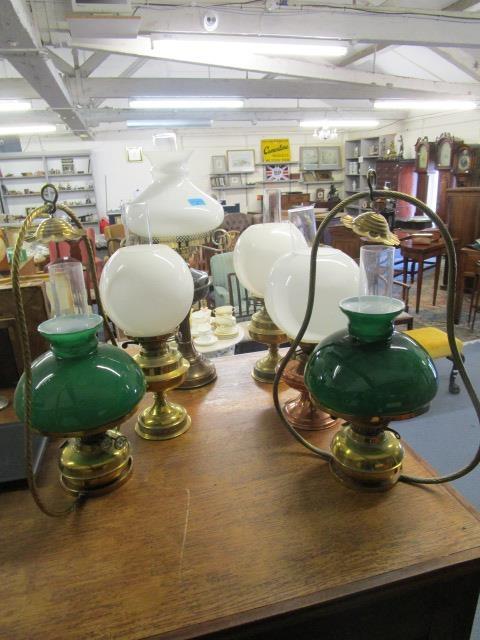 A group of four brass and copper oil lamps with glass shades and smoke funnels to include a Duplex