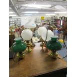 A group of four brass and copper oil lamps with glass shades and smoke funnels to include a Duplex