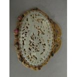 A Chinese oval, green jade plaque set within a gilt metal filigree surround, having nine natural set