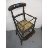 A Victorian stained wood child's high chair with a bar back and caned seat