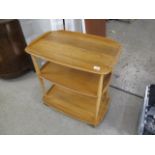 A light Ercol three tier trolley and a pair of Ercol three tier what nots, together with a light
