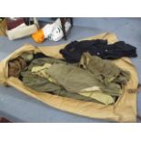 A military folding bed with various items of clothing, to include a policeman's coat, a wool jacket,