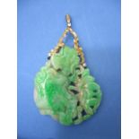 A green and grey carved jade pendant decorated with flowers and an insect set in a white, yellow and